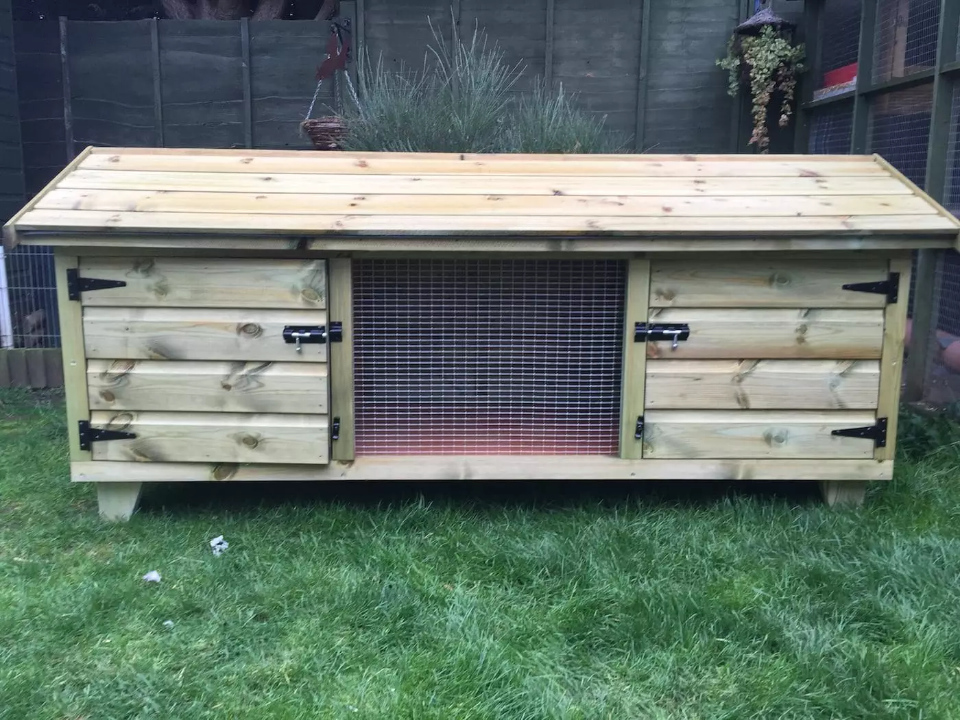 6ft British Giant XL Rabbit Hutch featuring a large wooden design with a hinged roof and wire mesh front, set on a grassy lawn.