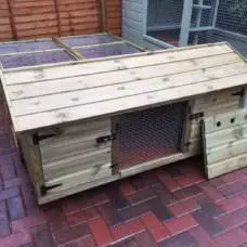 The 5ft British Giant Large Rabbit Hutch + 6ft Run is positioned on the brick patio, featuring an open door, hinged roof, mesh window, and solid panels.