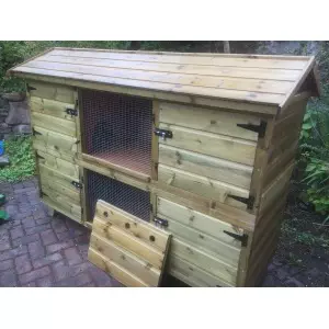 a wooden chicken coop on a brick surface