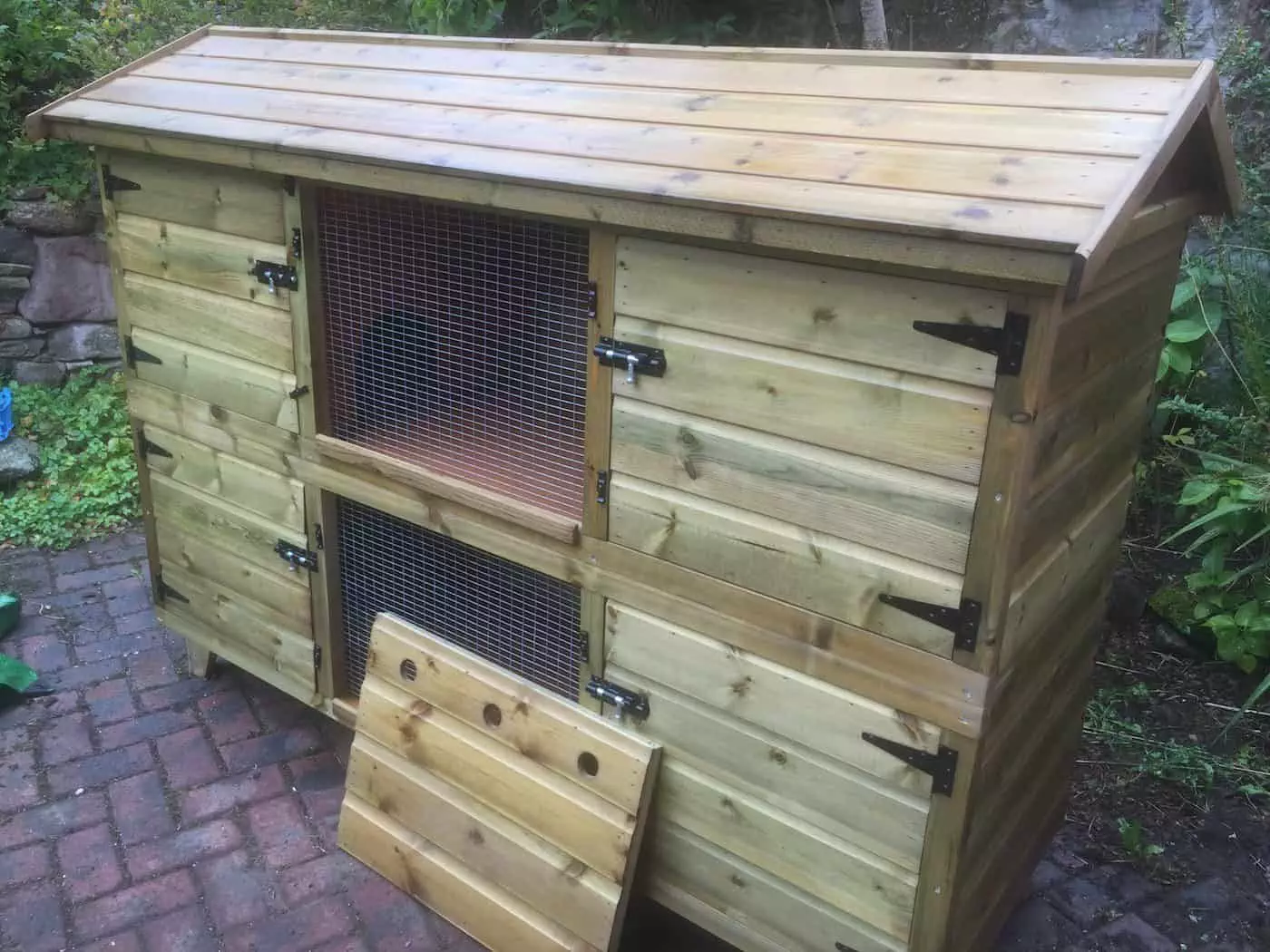 a wooden chicken coop on a brick surface